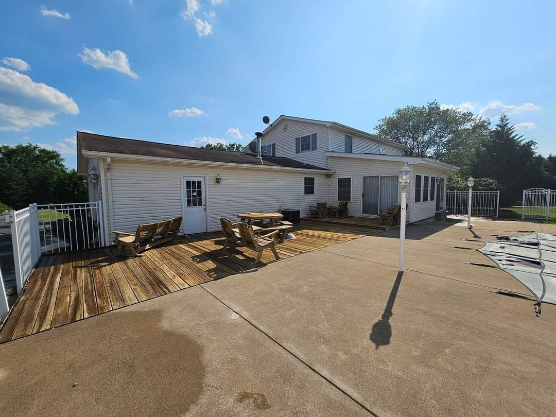 White house with deck and swimming pool on a sunny day.