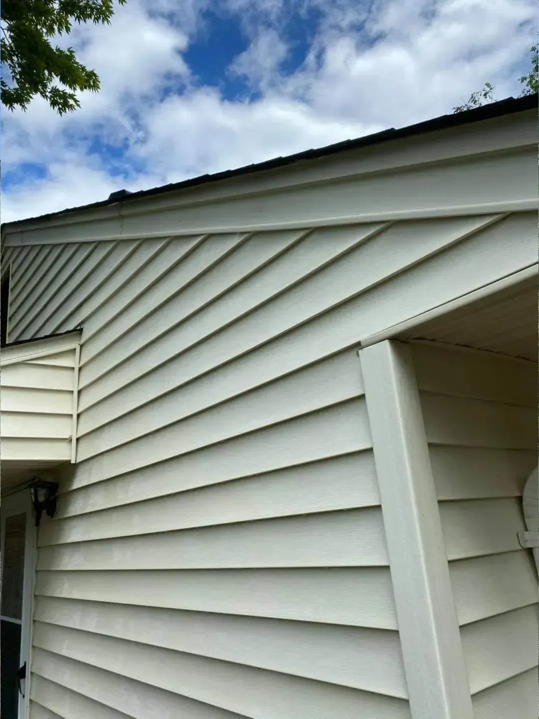Cream-colored siding on a house under a partly cloudy sky.