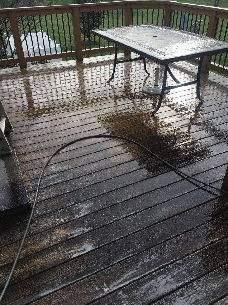 Wet wooden deck with a table and a hose on it.