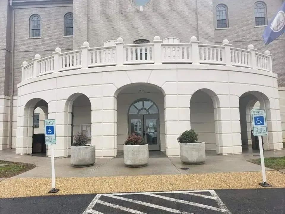White building entrance with arched walkways and accessible parking signs.