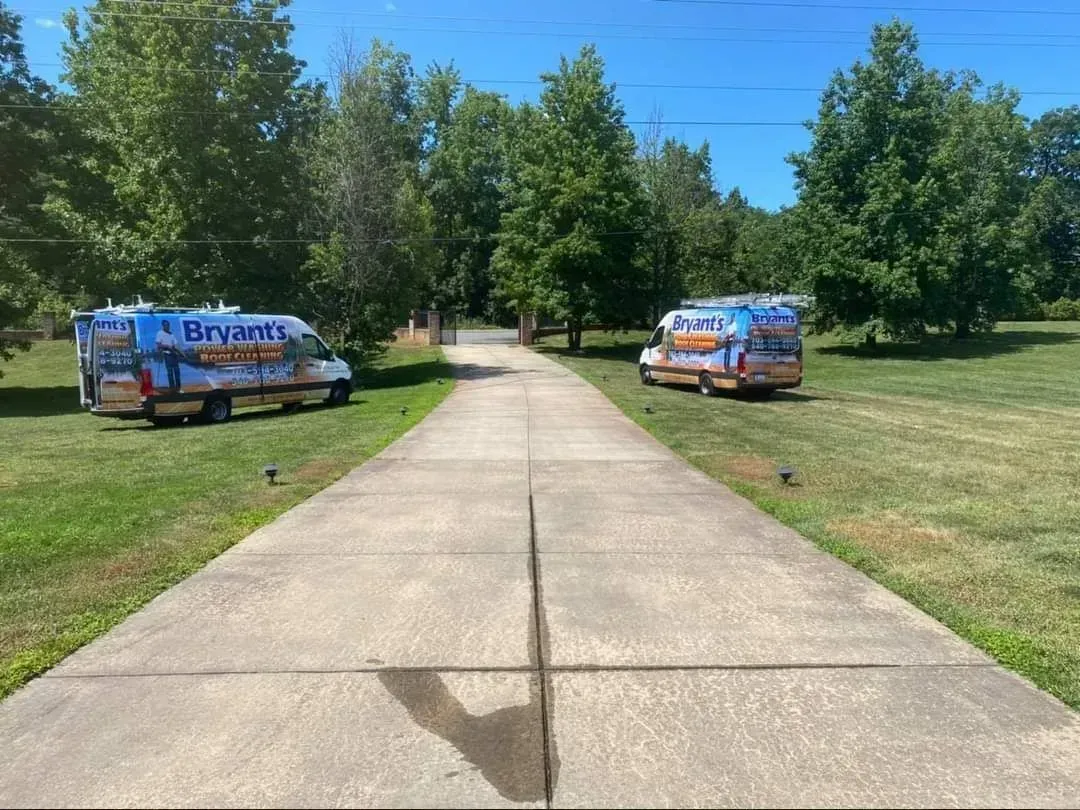 Two Bryant's Heating and Cooling vans parked on either side of a concrete driveway, trees in background, sunny day.