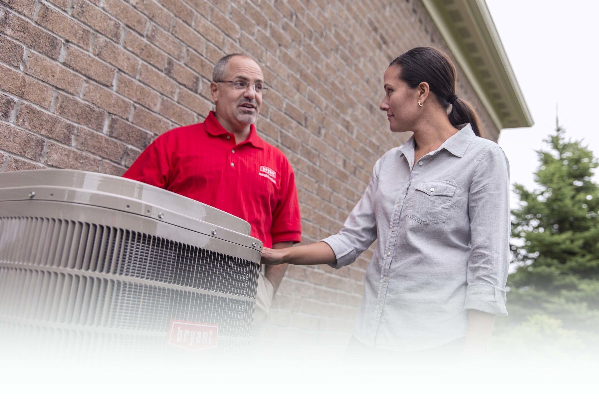 A man and a woman are standing next to each other in front of a brick building.