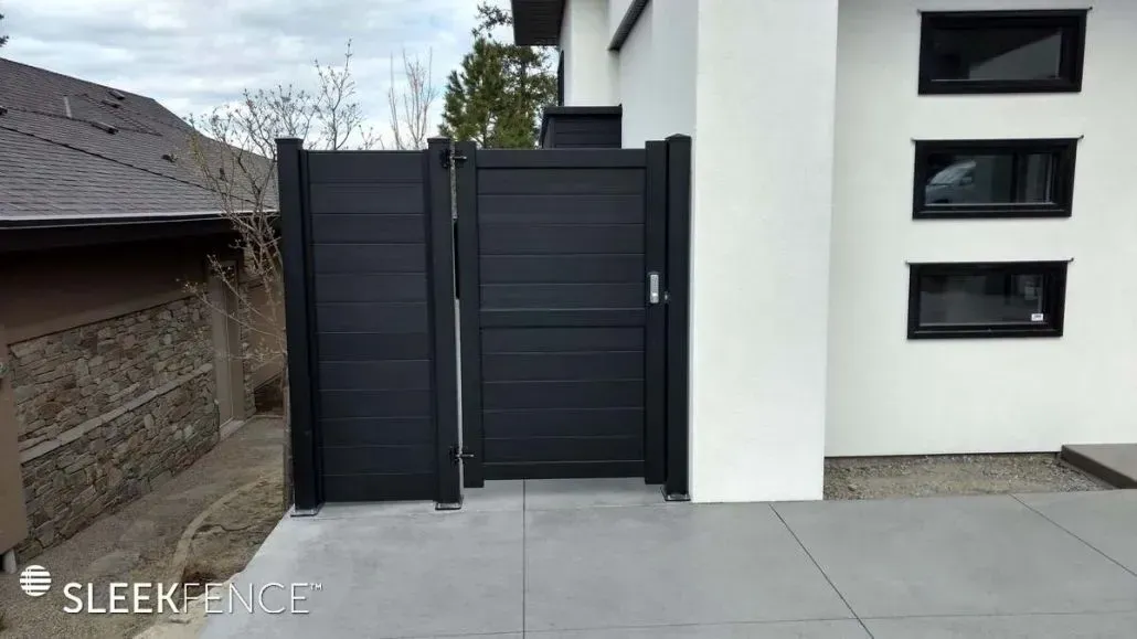 Black gate in front of a white building with small rectangular windows.