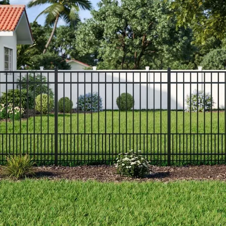 Black metal fence in a yard, with green grass and bushes, white house in background.