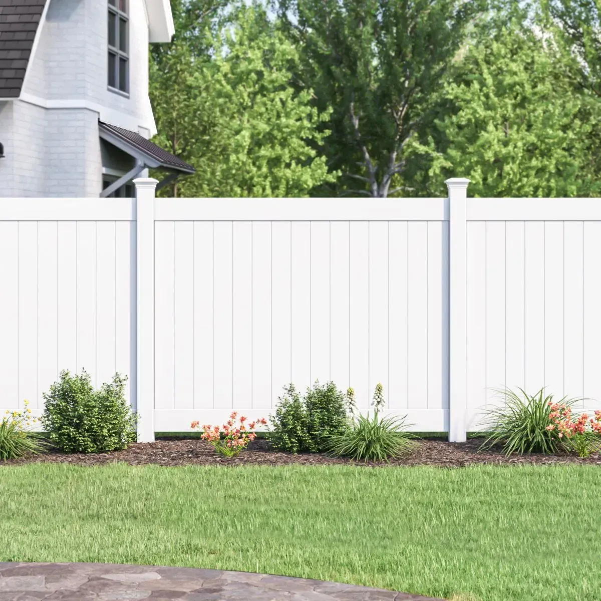 White picket fence bordering a yard with green grass and shrubbery, house in background.
