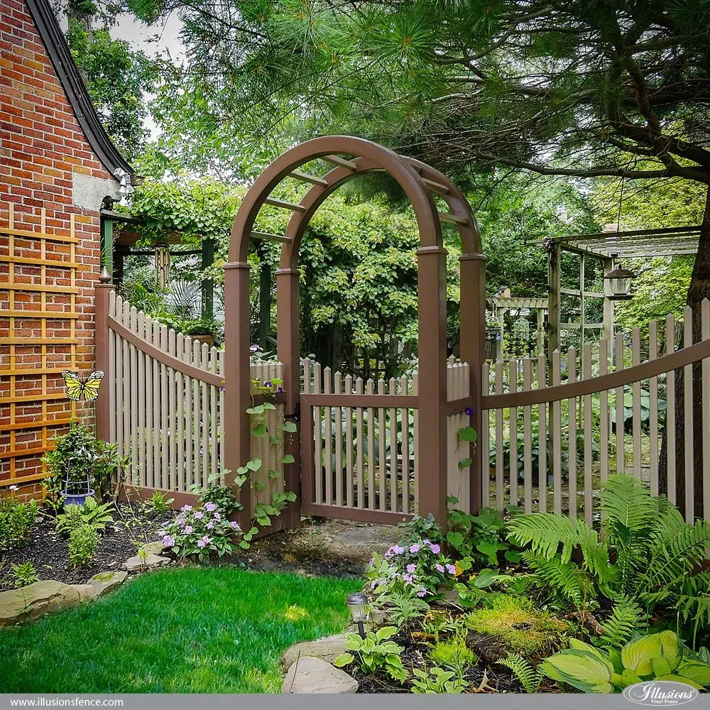 Brown arched wooden garden gate and fence with flowers and greenery.