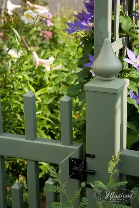 Green painted garden gate with climbing flowers in a lush garden.