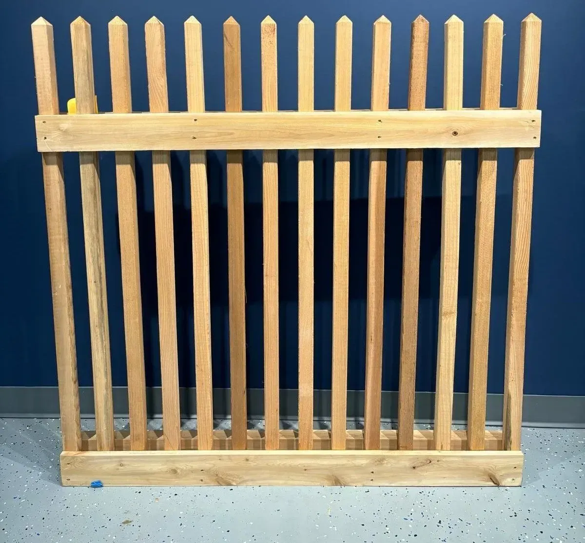 Wooden picket fence against a blue wall.