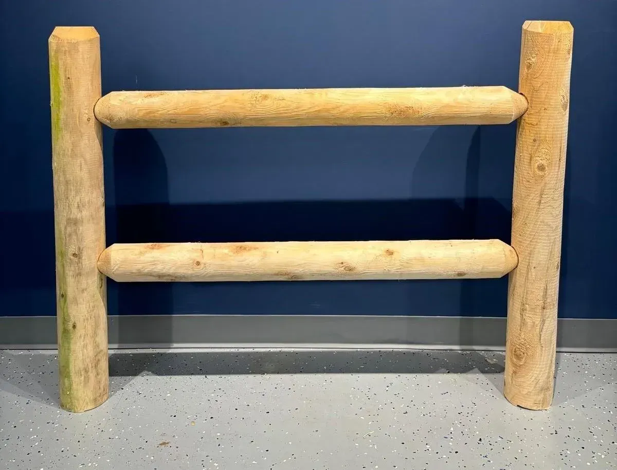 Wooden ladder-like structure with two horizontal bars between two vertical posts, against a blue wall.