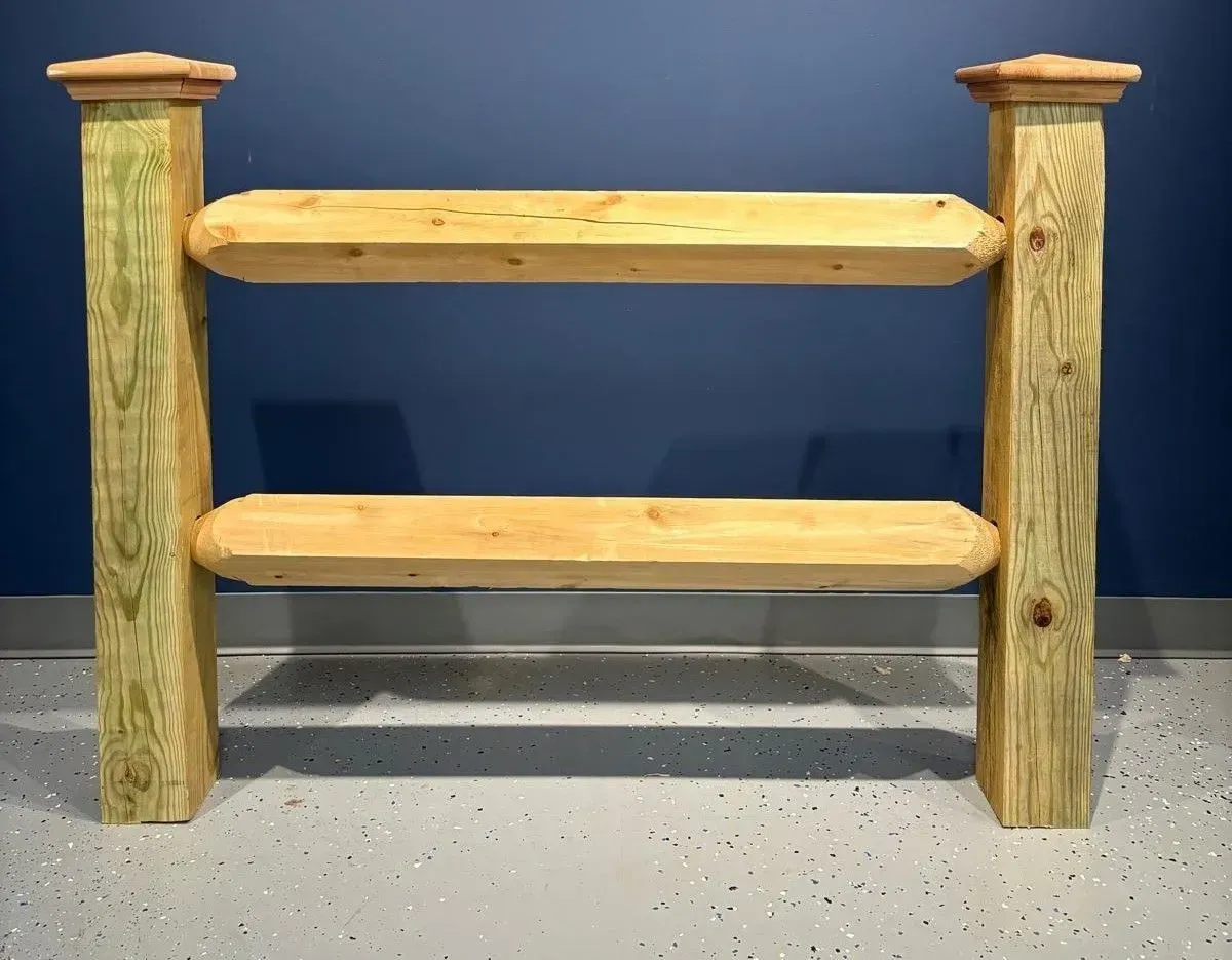 Wooden two-rail fence section with decorative posts, against a blue wall and gray floor.