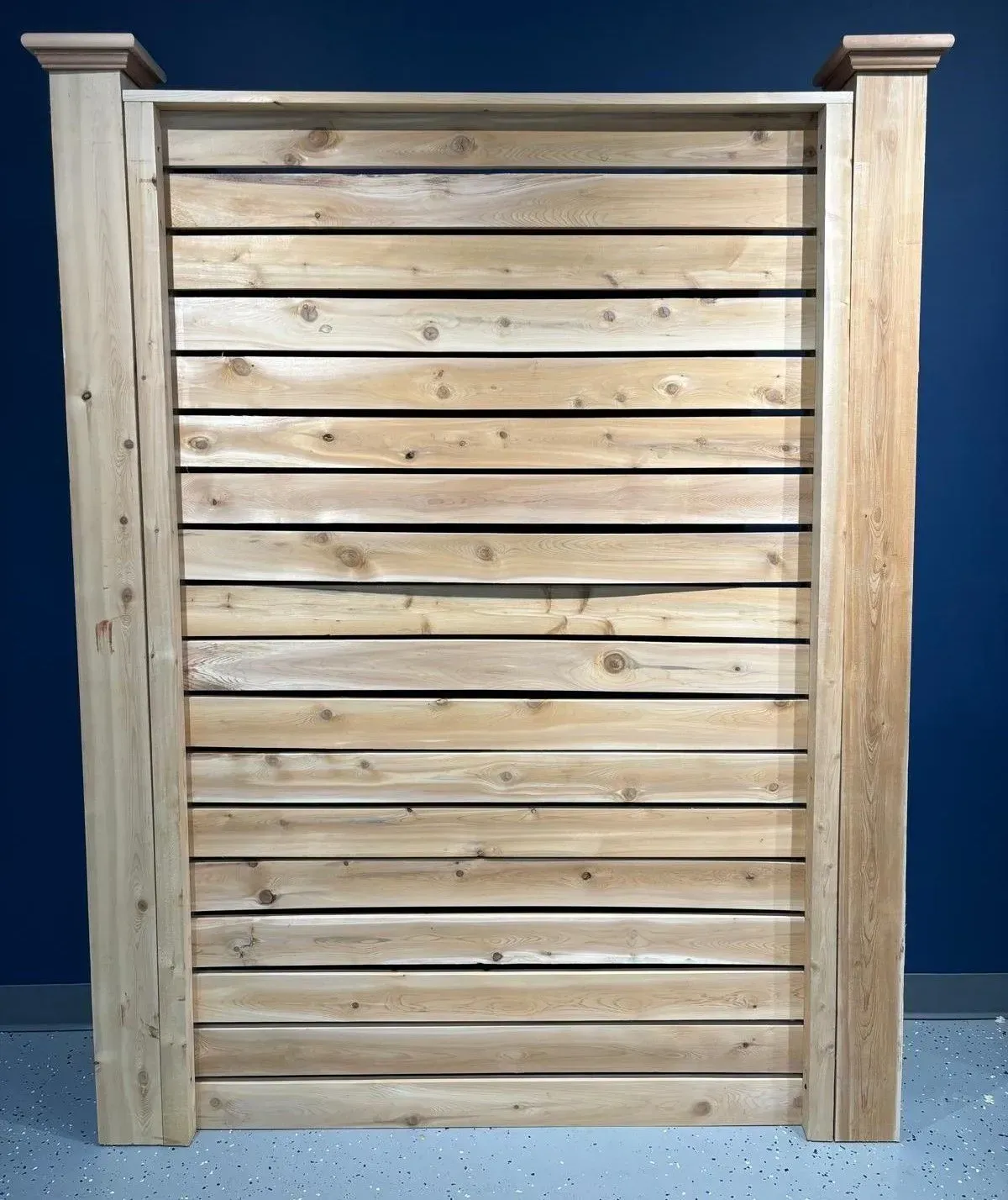 Wooden privacy fence with horizontal planks and decorative posts.