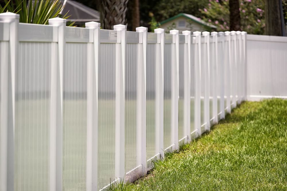 White vinyl fence in a yard with green grass.