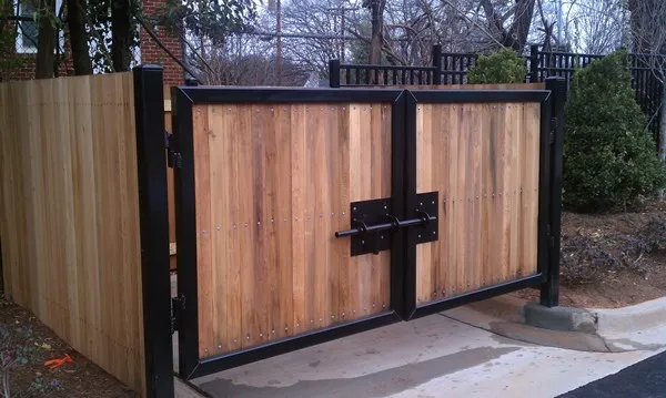 Wooden gate with black metal frame and latch, enclosed by wooden fence.