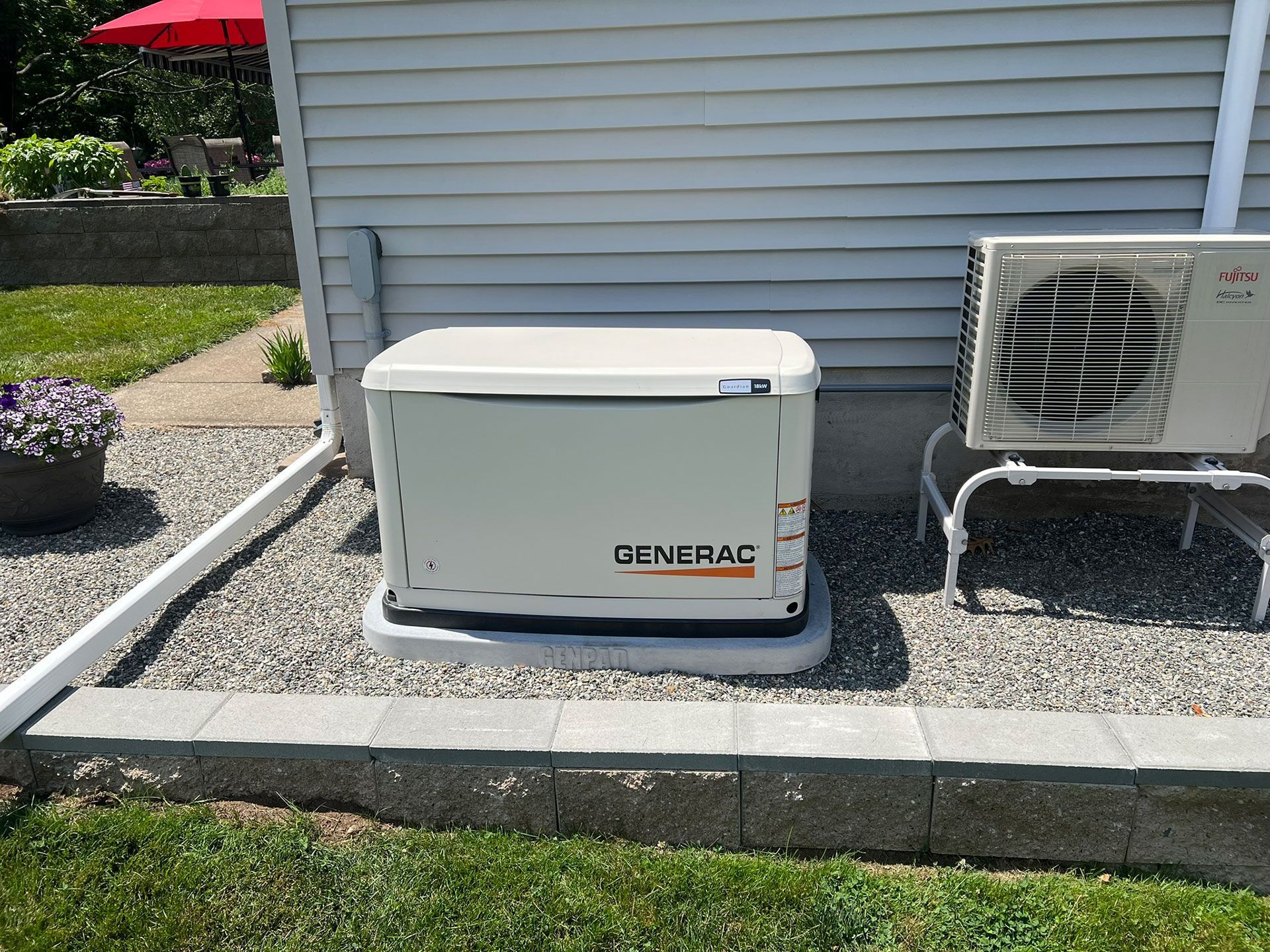 A generator is sitting outside of a house next to an air conditioner.