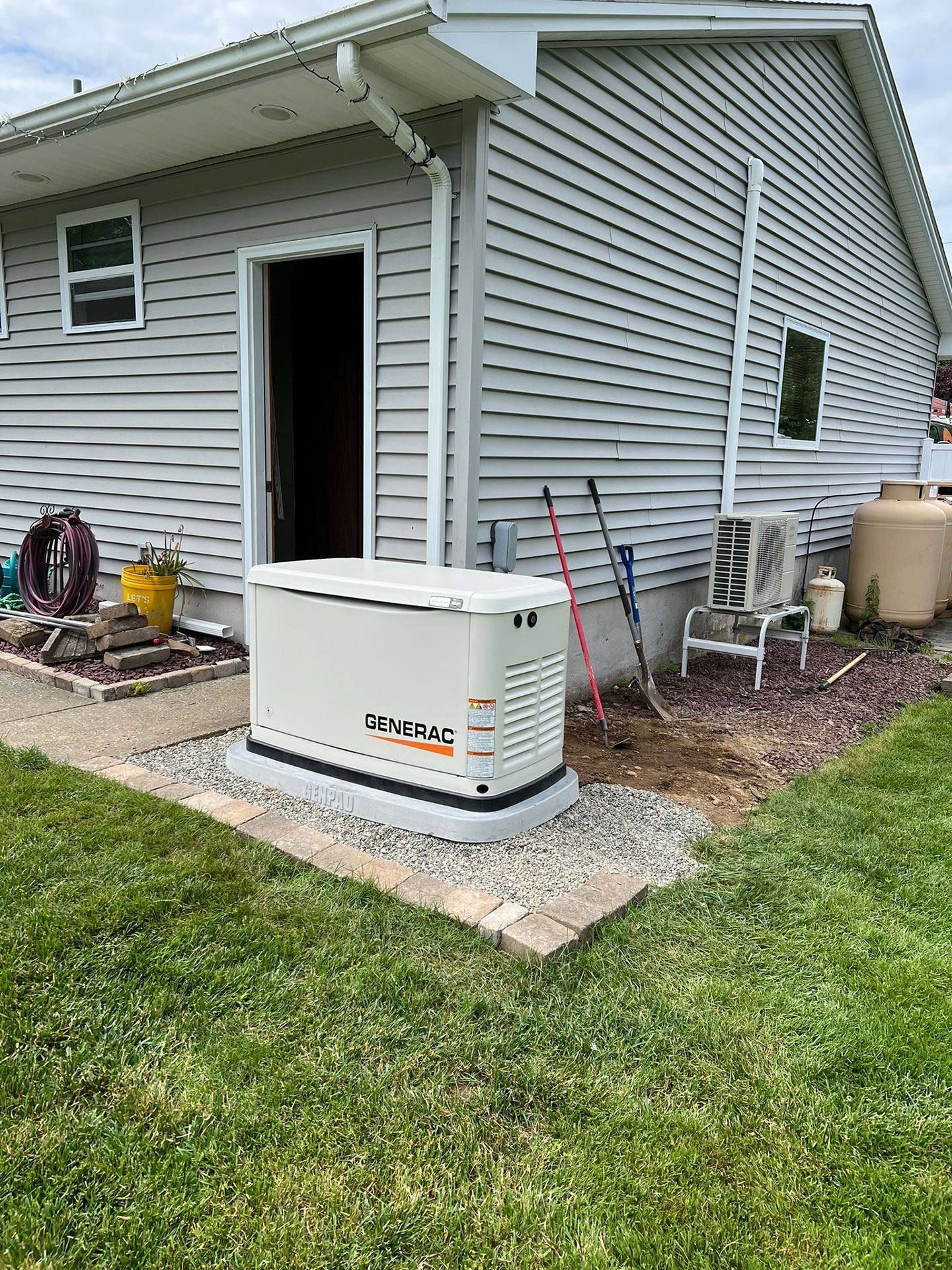 A generator is sitting in the backyard of a house.