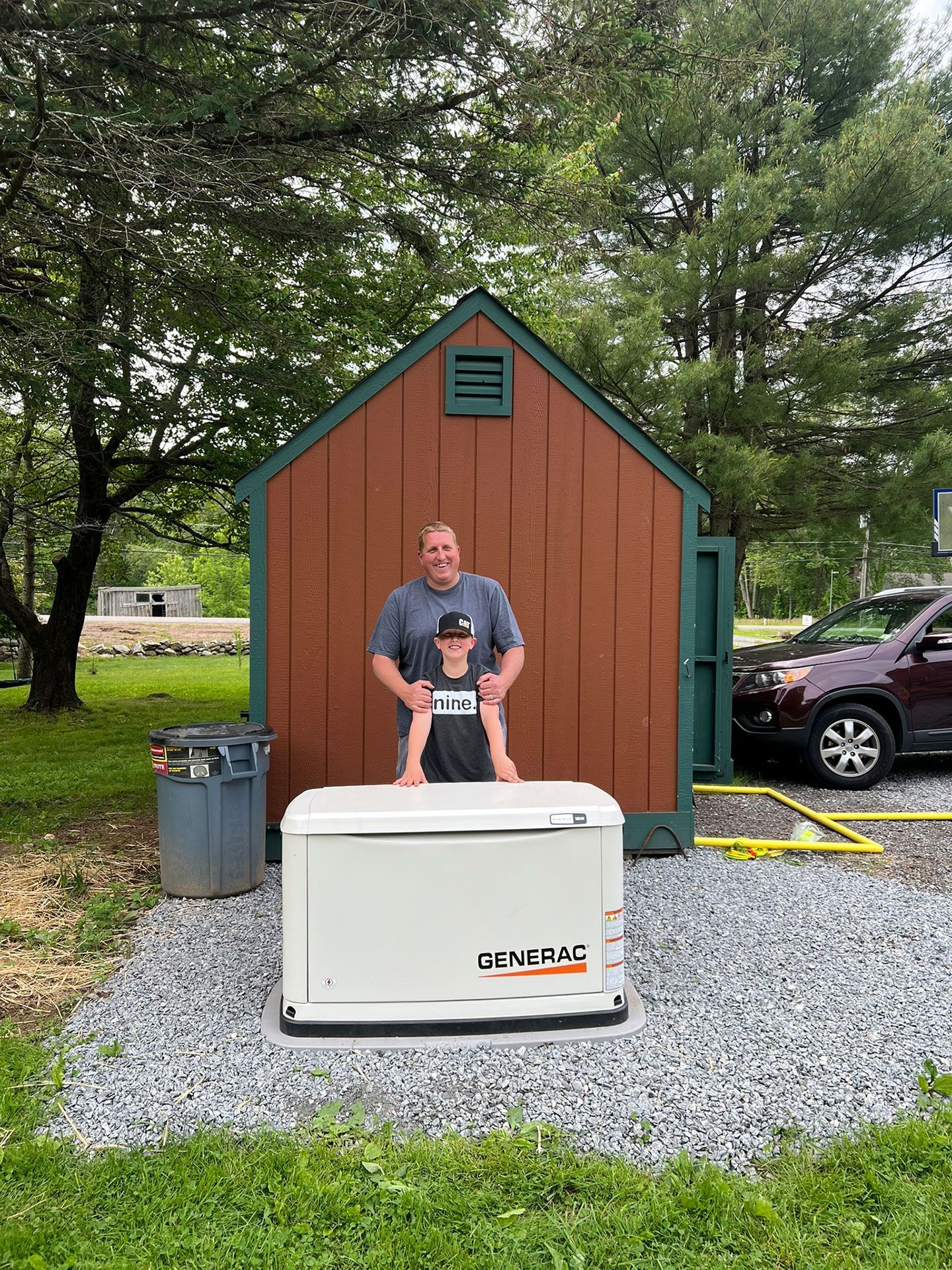 A man is standing in front of a shed next to a generator.