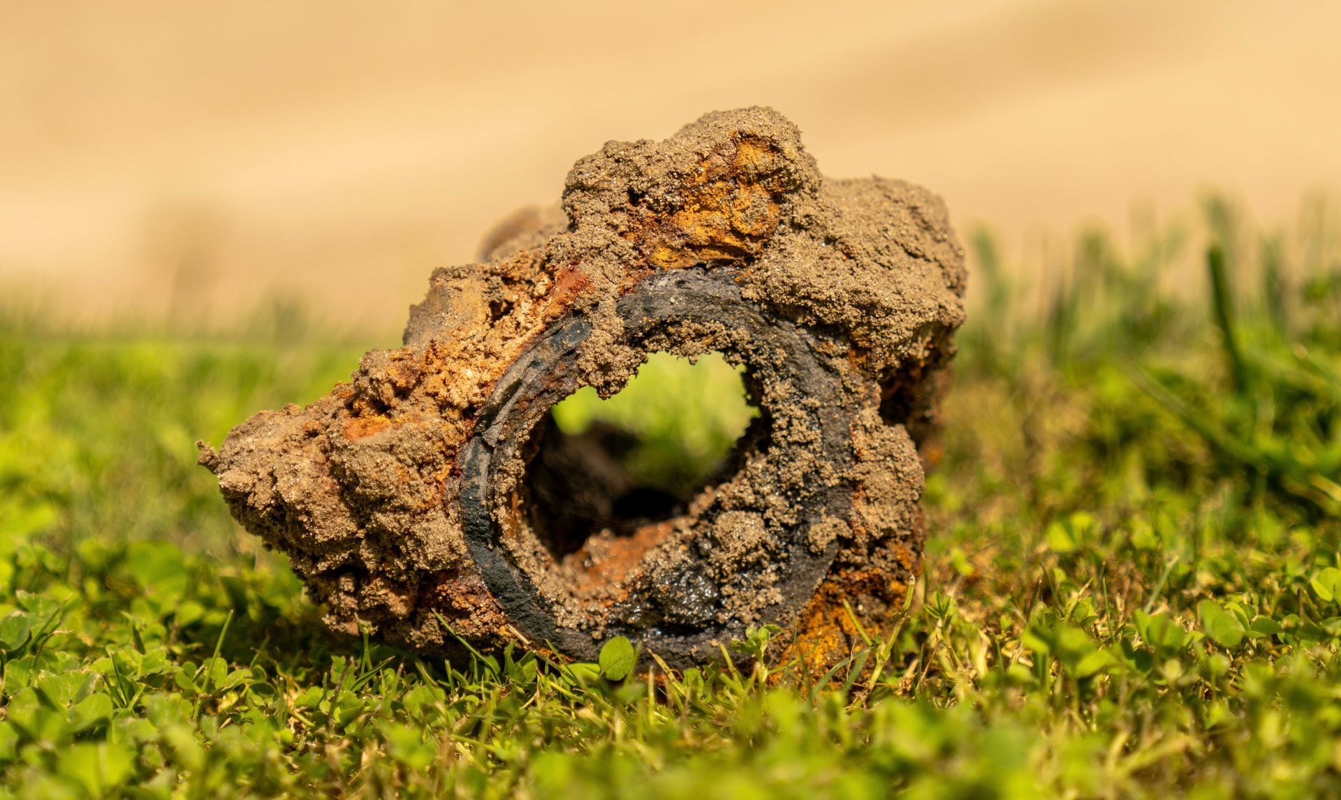 A piece of rusty metal is sitting in the grass.