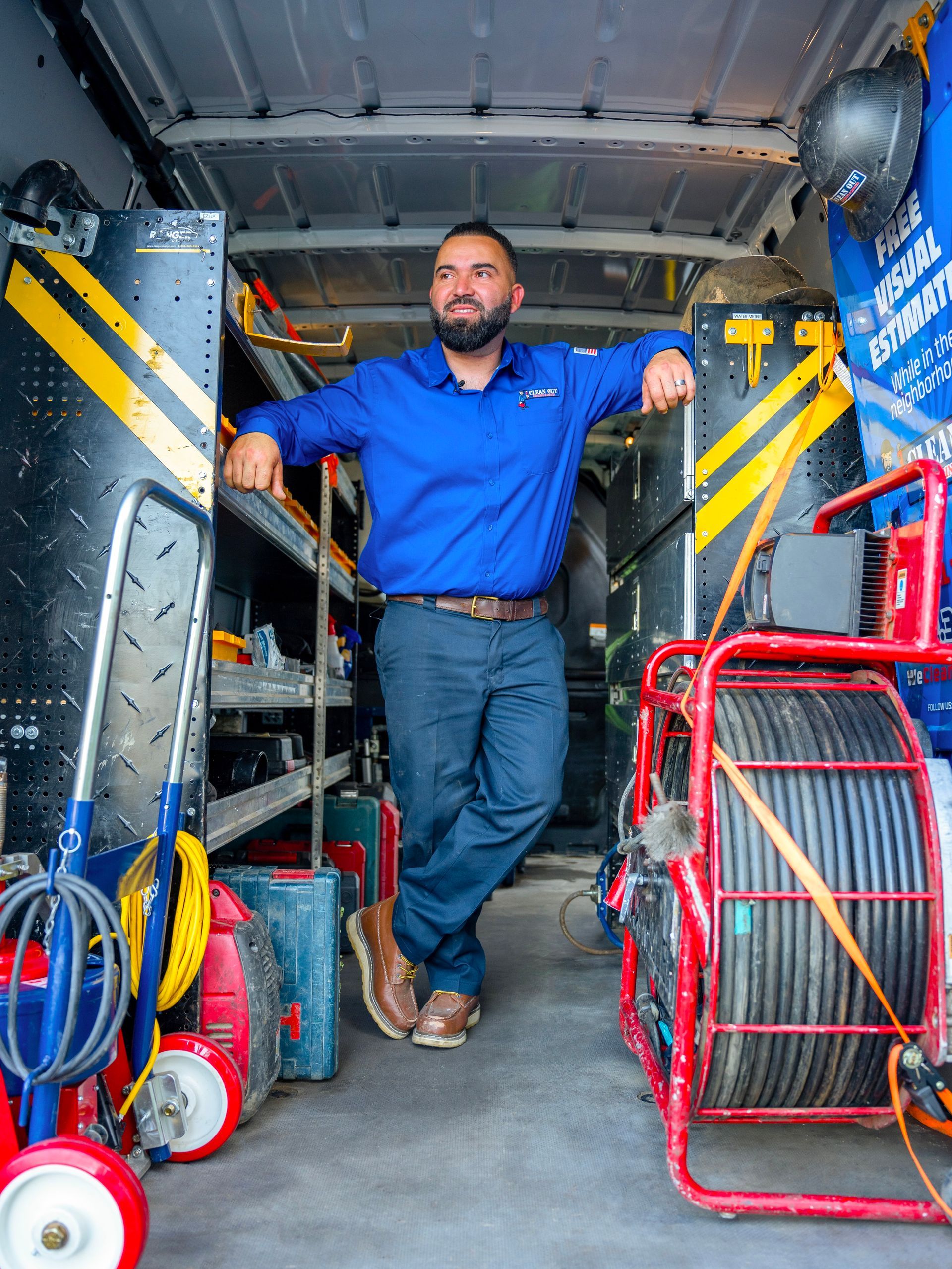 A man in a blue shirt is standing in the back of a van.