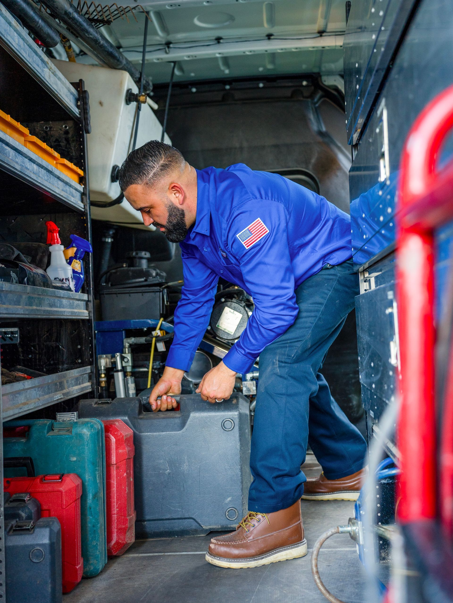 A man in a blue shirt is working in the back of a van.
