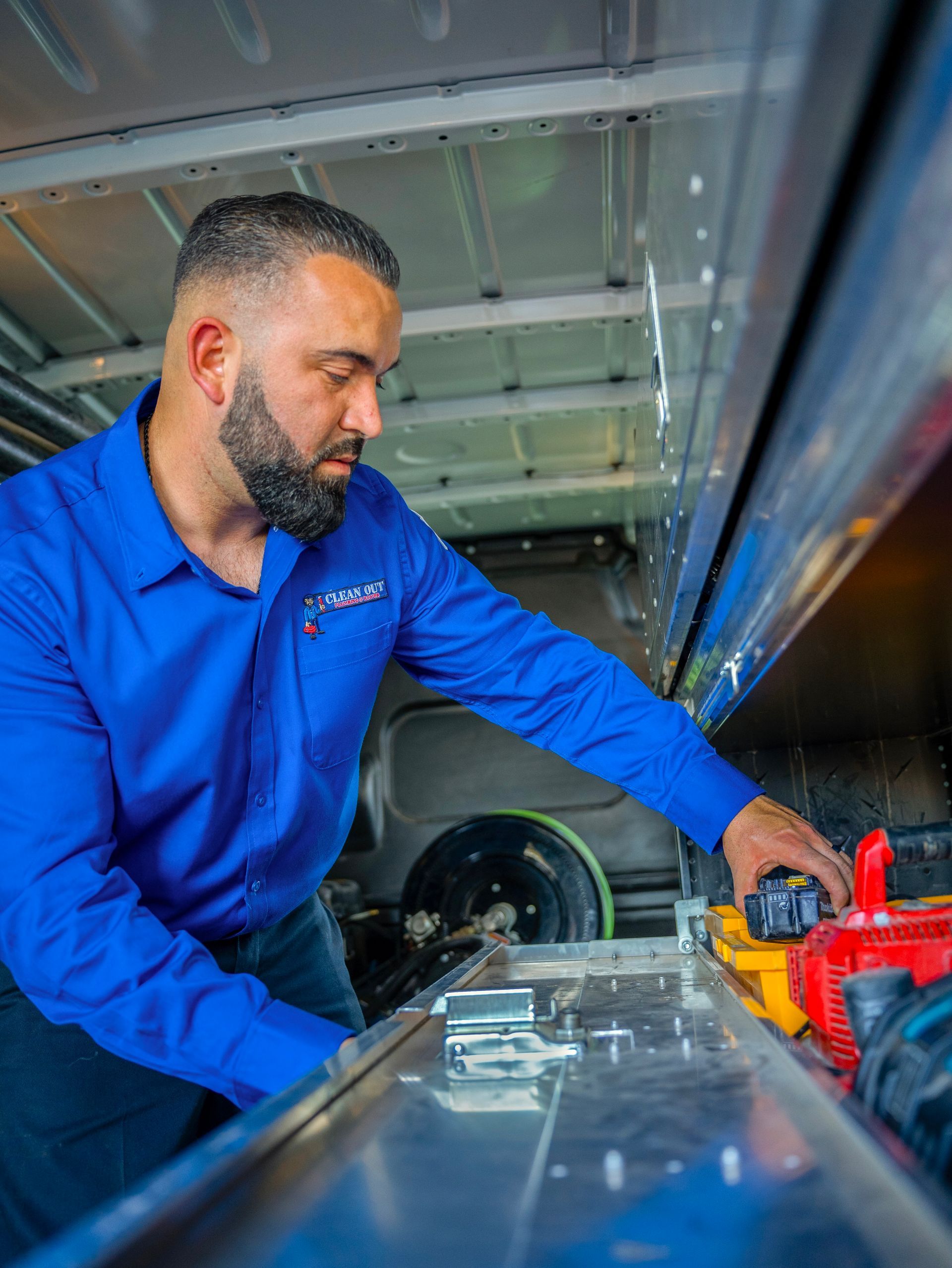 A man in a blue shirt is working on a machine in a van.