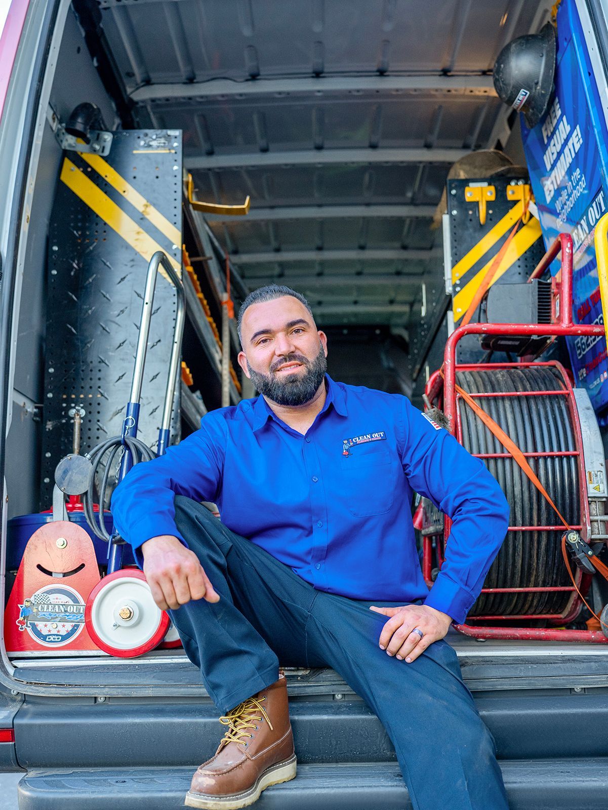A man is sitting on the back of a van.