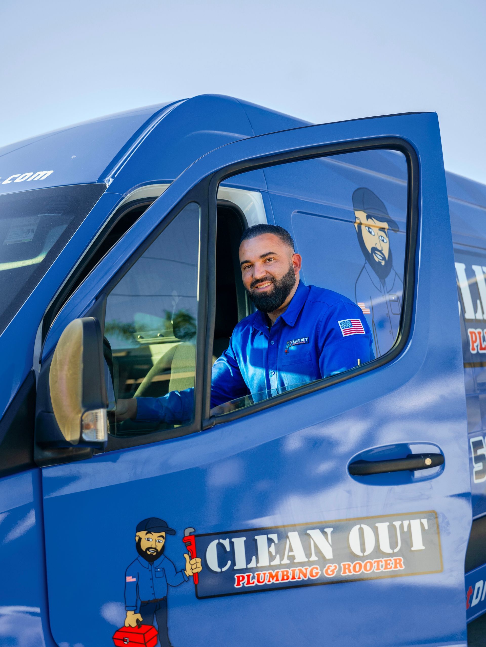 A man is sitting in the driver's seat of a blue van.