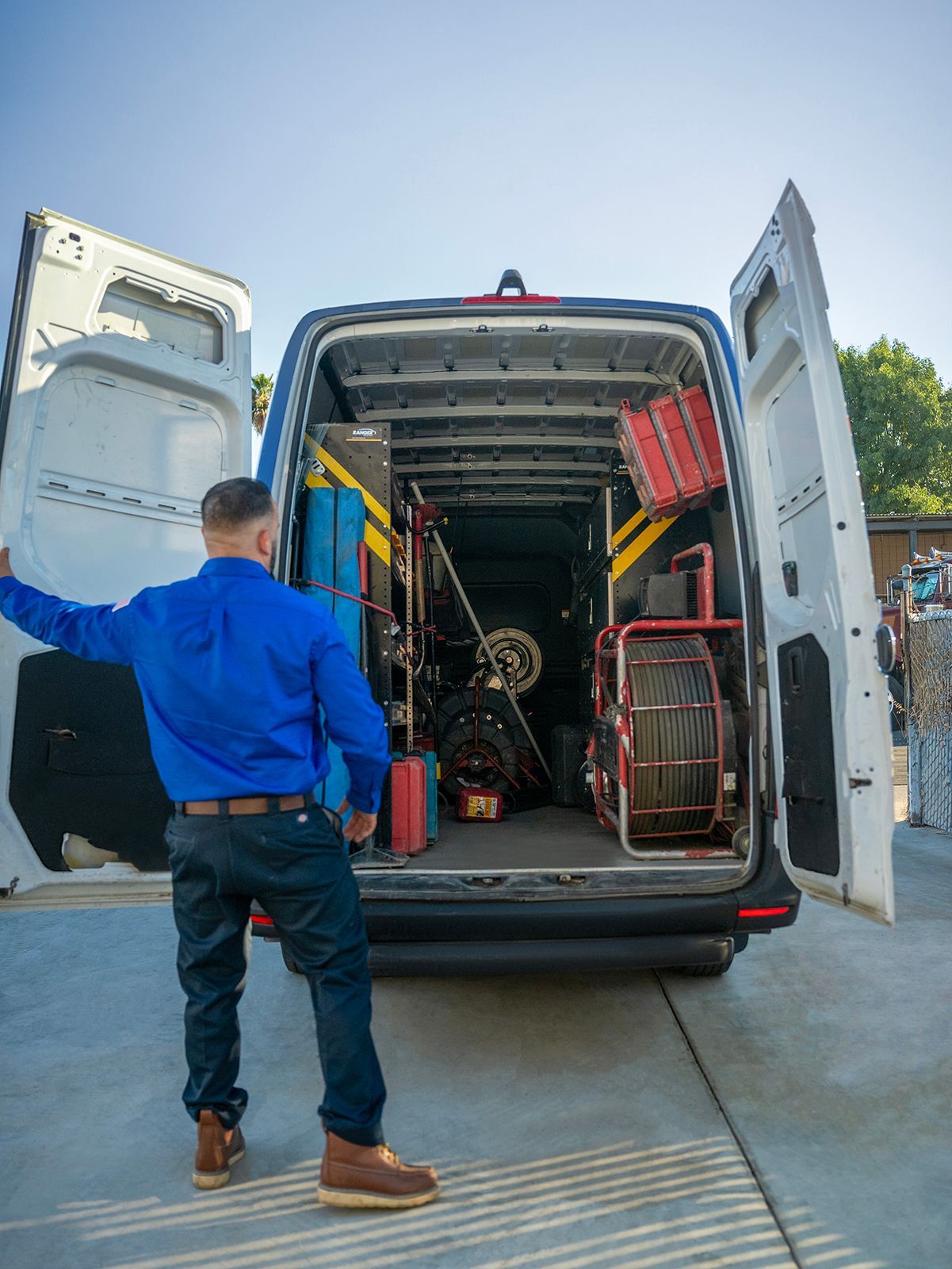 A man is standing in front of a van with the door open.