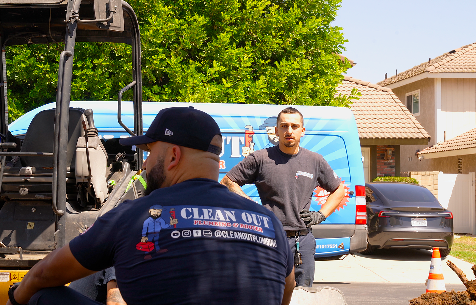 Two men are standing in front of a van that says clean out.