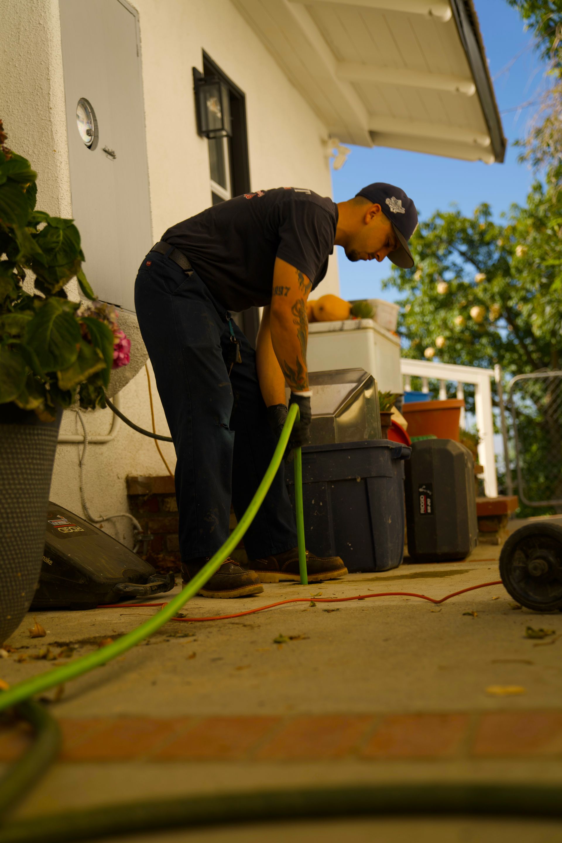 A man is holding a green hose in front of a house.