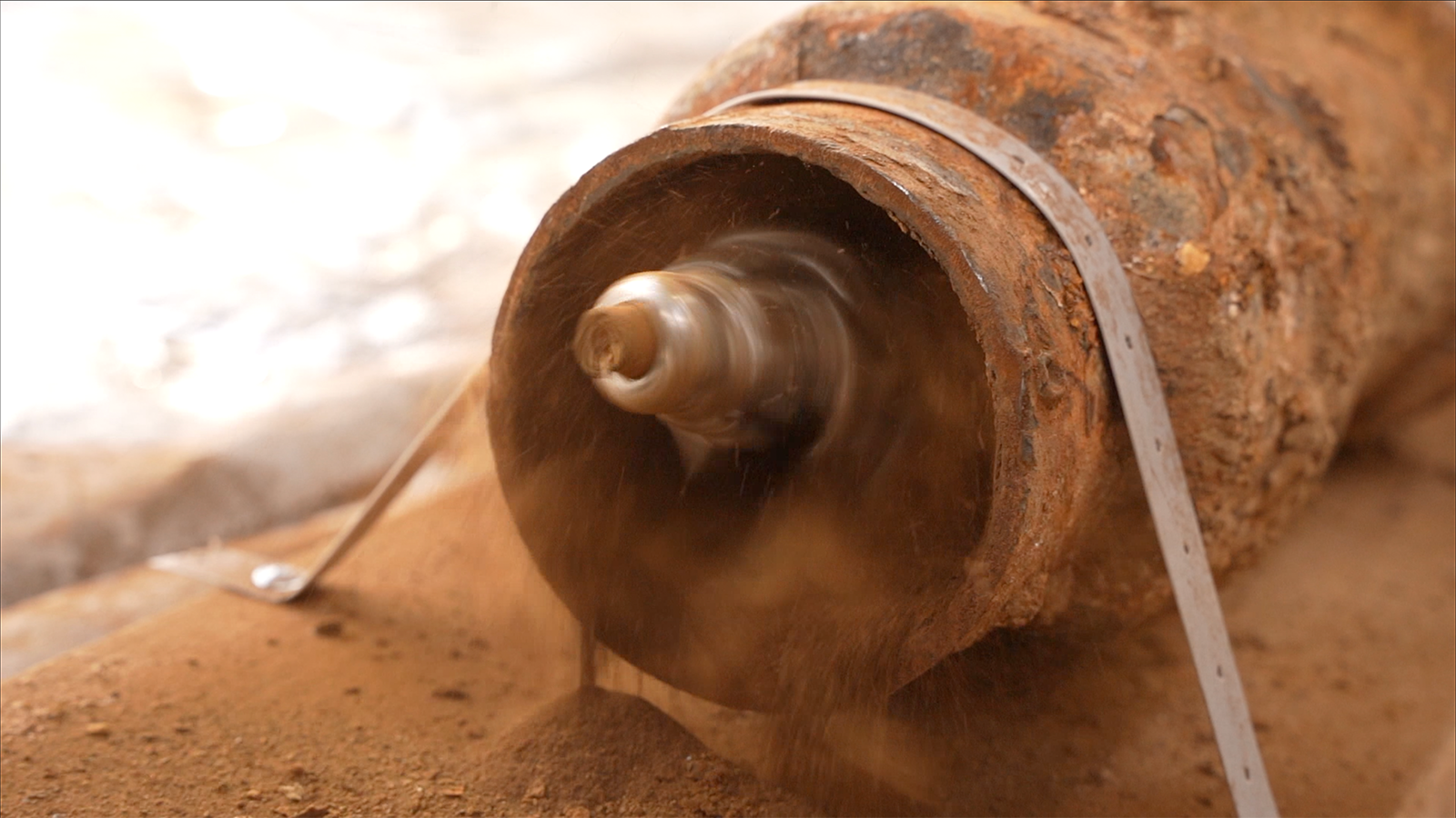 A close up of a rusty pipe with a tape measure attached to it.