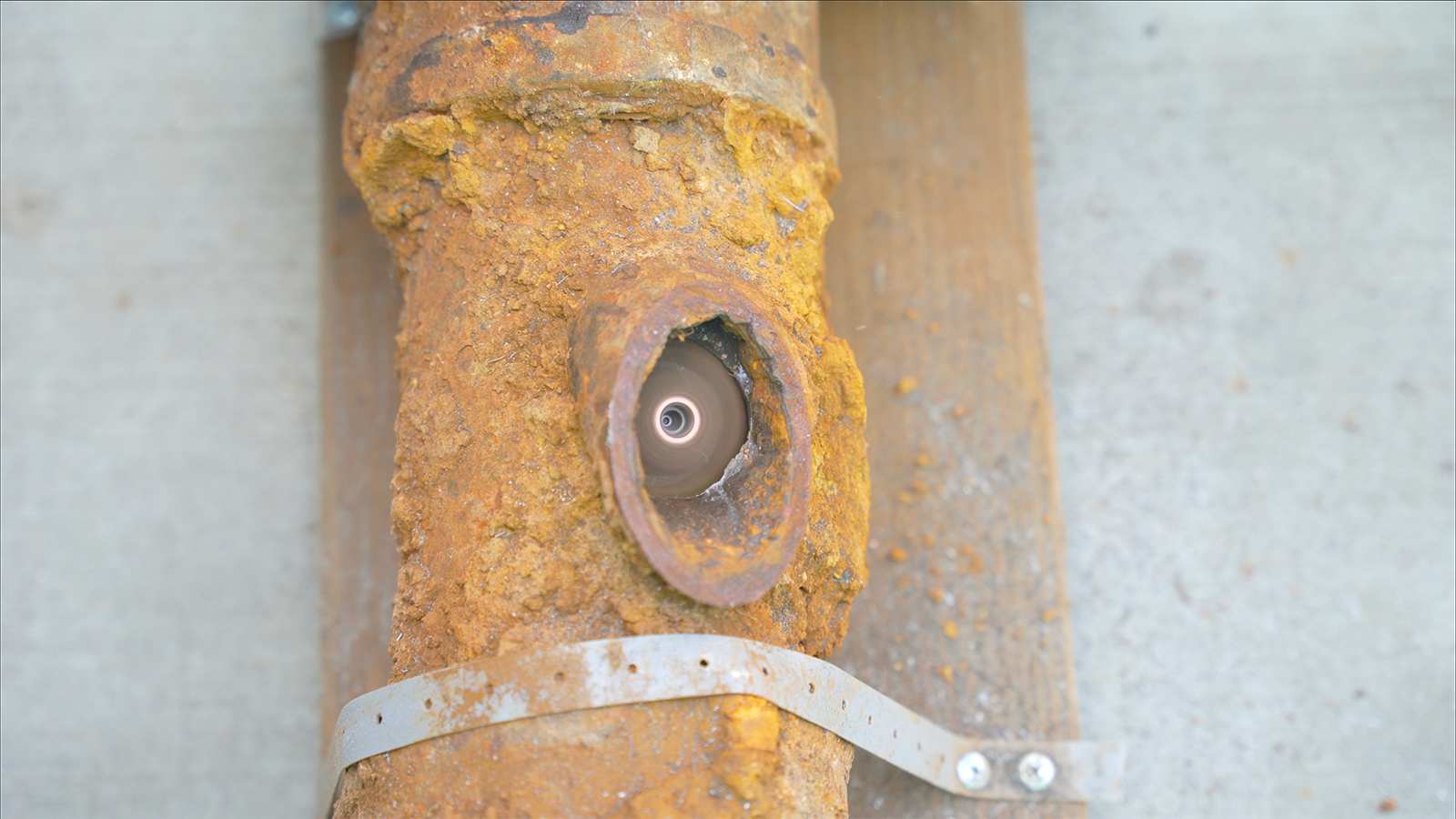 A close up of a rusty pipe with a hole in it.