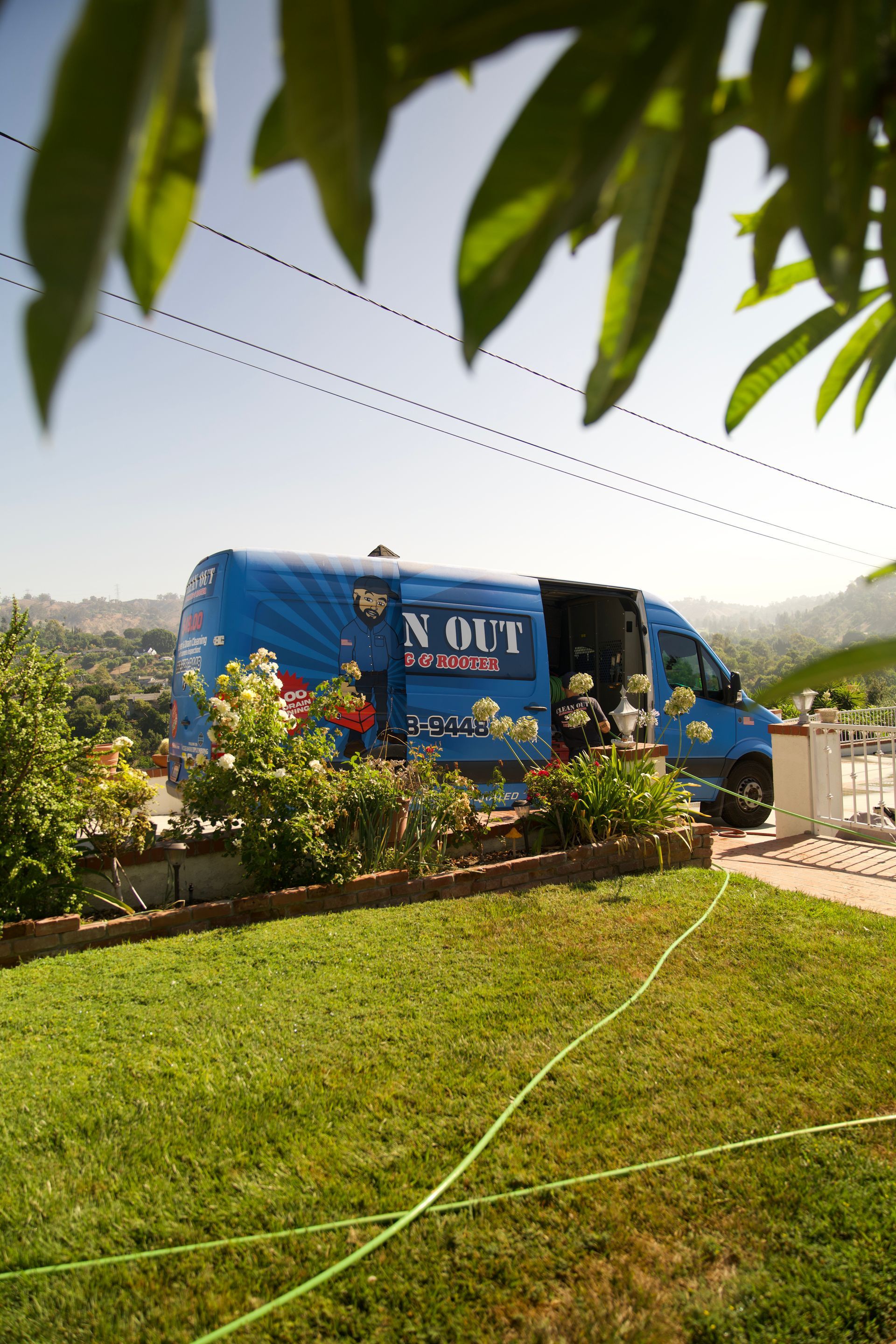 A blue van is parked in a lush green yard.
