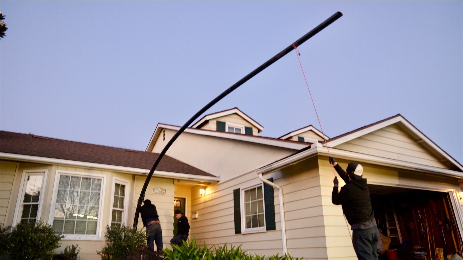 A man is holding a pole in front of a house.