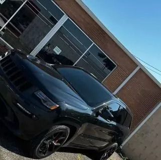 Black Jeep SUV parked in front of a building with tinted windows.