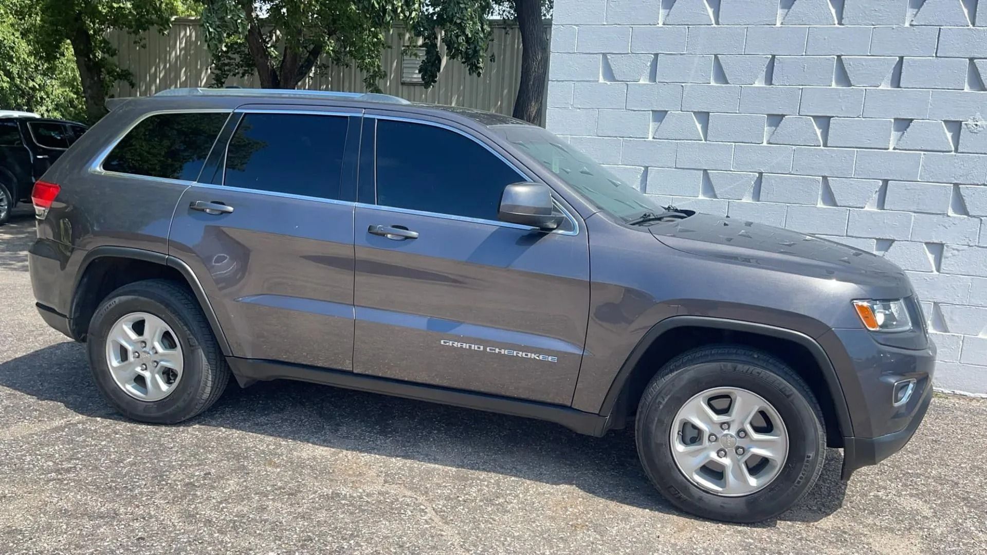 Gray Jeep Grand Cherokee parked beside a textured white wall.