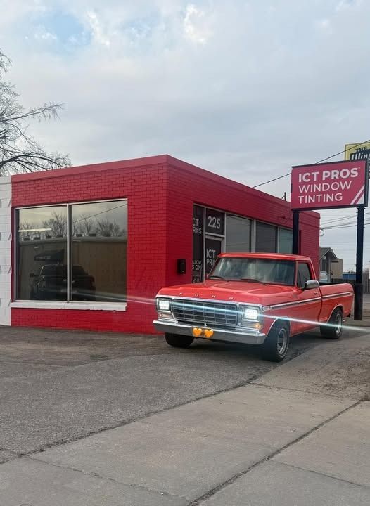Red pickup truck parked outside of a red and white building, 