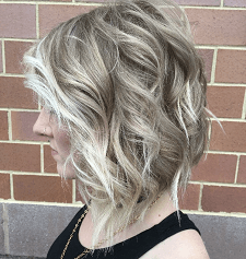 A woman with blonde hair is standing in front of a brick wall.