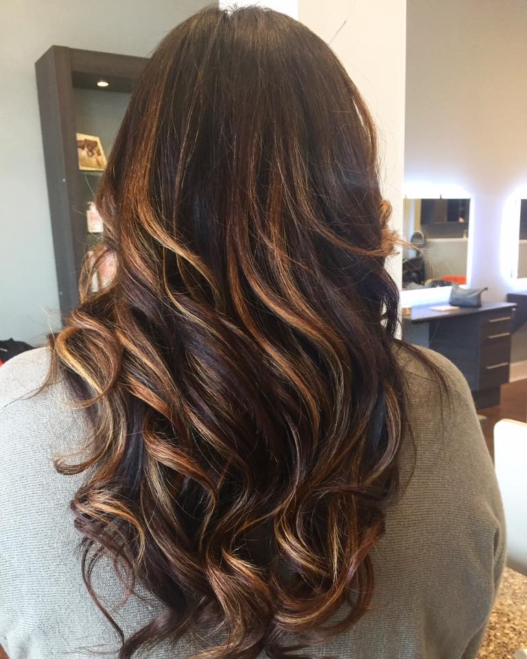 A woman with long brown hair is standing in front of a mirror.