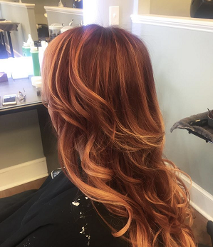 A woman with long red hair is sitting in a chair.