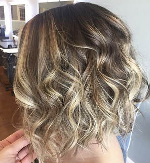 A woman with curly hair is getting her hair done in a salon.