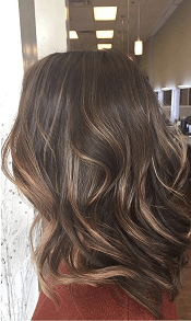 A woman with long brown hair is standing in a salon.