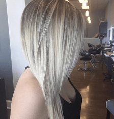 A woman with long blonde hair is standing in a salon.
