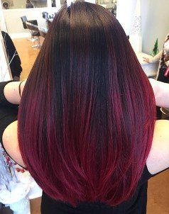 A woman with black and red hair is standing in a salon.