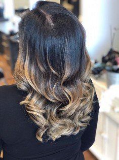 A woman with long black hair and blonde highlights is wearing a black shirt.