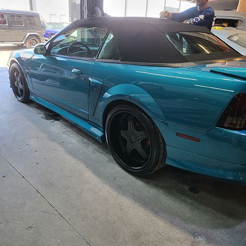 A blue mustang convertible is parked in a garage.