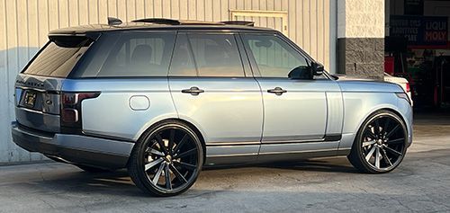 A silver range rover is parked in front of a garage.