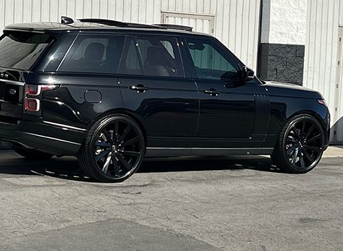 A black range rover is parked in a parking lot in front of a building.