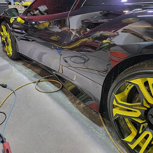 A black car with yellow wheels is parked in a garage.