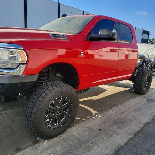 A red ram truck is parked on the side of the road.