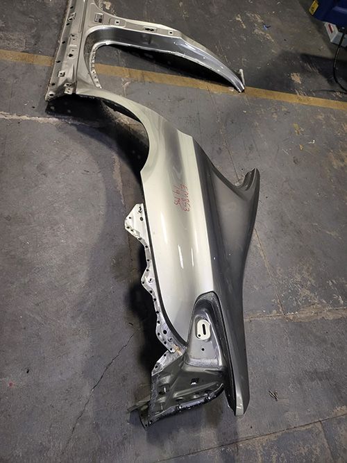A car fender is sitting on the ground in a garage.